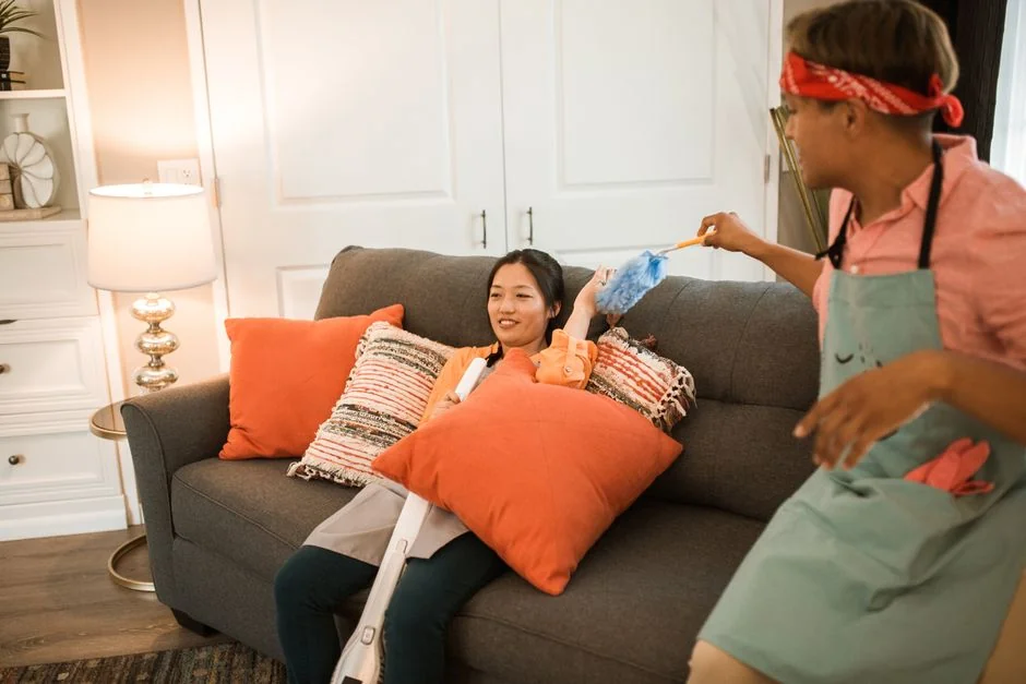 a-woman-in-a-green-shirt-and-black-gloves-vacuuming-a-gray-ottoman-5txz228u4eo